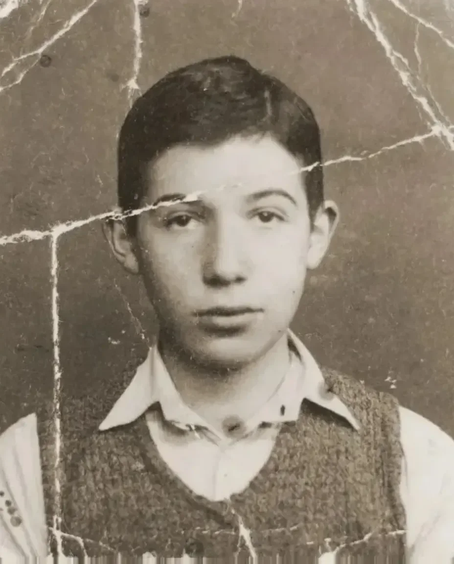 A boy in a knitted vest, the print broken by deep cracks across his face, and the same portrait repaired and in color
